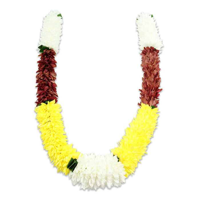 Displayed against a clean white background with a soft shadow that imparts gentle dimensionality, this U-shaped ceremonial garland is an exercise in rhythm and colour. Expertly assembled from many thousands of fabric petals, the composition begins at each upper tip with a dense, cylindrical section of creamy white that looks like clustered chrysanthemums-airy in profile, soft to the eye. That white segues into a compact band of maroon-deep, almost terra-cotta in warmth-whose tightly packed petals give a sense of solidity and reverence. The garland then pours downward into the longest, most generous section: bright yellow blooms crafted to resemble marigolds, forming the broad, plush sweep of each arm and carrying the piece with cheerful luminosity. Where the two yellow extremes meet, a fuller cluster of pure white blossoms sits at the centre bottom, serving as a bright focal point. Small dark-green leaf-like accents are thoughtfully placed between colour shifts, particularly between yellow and white, offering visual rest and a hint of botanical realism.Described here with the eye of a local Notting Hill florist who supplies ceremonial garlands for families and temples around Ladbroke Grove and Holland Park, the piece feels both substantial and tender-built to be held, draped over a deity, or worn at a traditional wedding. The fabric petals have a soft matte sheen rather than gloss, and the construction prioritises longevity for repeated festival use, whether for a Diwali mandap, a wedding ceremony, or a respectful offering at a temple.