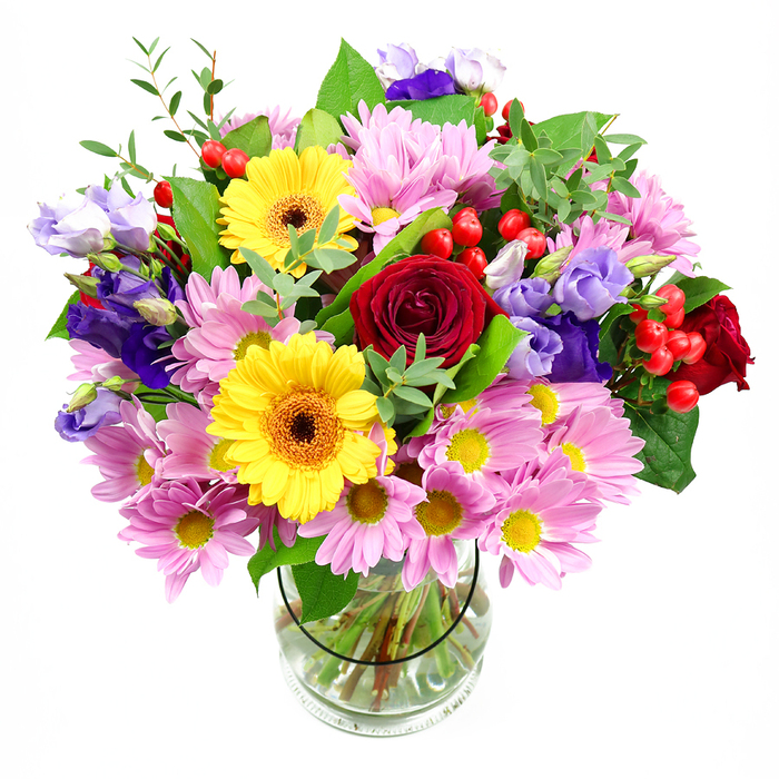 In this image, a tall, clear glass vase holds an abundant mixed bouquet, positioned against a pure white background that heightens the intensity of its colours. At the visual centre, rich deep red roses open in layered spirals, their velvety petals drawing the eye and anchoring the design with a sense of timeless romance. Nestled close by, two bright yellow gerbera daisies with dark, warm-toned centres add a ray of cheerful light, echoing the upbeat character of Notting Hill's cafés and boutiques around Westbourne Grove. Surrounding these focal blooms are generous clusters of soft pink daisies or chrysanthemums, their countless slender petals and tiny golden centres creating a textured, cloud-like ring of pastel colour. Threading through this softness are graceful purple and lavender lisianthus, their bell-shaped blossoms and slightly ruffled edges introducing cooler tones and an elegant, almost airy movement. Dotted throughout, glossy red hypericum berries sit like tiny polished beads, bringing both structure and playful detail. A variety of foliage in multiple greens-broad, deep-toned leaves and finer, light-green stems-cradle the flowers and add a sense of natural, garden-fresh abundance, as if the bouquet had just been gathered from a hidden courtyard garden off Pembridge Road. The transparent vase allows a clear view of the neatly arranged stems submerged in clean water, showcasing the careful craftsmanship of the florist. Soft, even lighting from above gently highlights each petal and leaf, making this bouquet feel inviting, joyful, and perfect for birthdays, thank-you gestures, or simply brightening a home in Notting Hill with an elegant burst of nature.