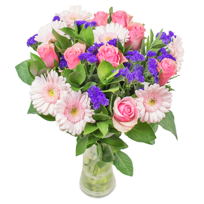 Elegantly poised within a gently sculpted clear glass vase, this locally handcrafted bouquet is a vibrant celebration of Notting Hill's creative heart. At the core, 7 to 9 soft and medium pink roses display petals in various states of unfurling-some tightly closed, others opening to reveal their classic spirals-each offering a testament to romance and renewal that echoes the everyday beauty found along Kensington Park Road. Interspersed among the roses, 5 to 7 pale pink Gerbera daisies add brightness and generosity with their large, symmetrical heads and almost-white centers, reminiscent of the early blooms in a Westbourne Grove courtyard. Clusters of vivid purple statice punctuate the arrangement, introducing a striking contrast and playful textural flair, much like the creative bursts of color scattered across Notting Hill's doorstep gardens. Lush, deep green foliage weaves throughout, enhancing the bouquet's sense of abundance and providing a fragrant, organic foundation. The vase, transparent and brimming with fresh water, showcases the natural lines of each stem and signals the promise of freshness with each delivery. This artful composition, seamlessly blending roses, daisies, and purple statice, is at home on a Portobello market table or adorning a celebratory brunch by the Notting Hill Carnival route-perfect for expressing affection, marking life's milestones, or brightening any elegant home or office space with local spirit and joy.