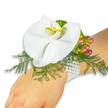 A single, sculptural Phalaenopsis orchid rests like a quiet jewel on the light-skinned wrist of a wearer, photographed against a pure white backdrop that isolates every surface and shadow. The orchid is immaculate white, its broad, satin-like petals unfolding gently around a small, luminous labellum streaked with bright yellow at the throat and a hint of deeper orange toward the centre; the bloom reads as both modern and timeless. Nestled beneath and around the flower are fine, feathery fronds of asparagus fern, their bright green filigree creating a soft, breathable cushion that gives the corsage depth and movement without overwhelming the bloom. On one side a tight cluster of glossy hypericum berries arcs outward, their skins graduating from pale green through warm rose to a rich cranberry-red, offering a tactile contrast to the orchid's smoothness and a nod to autumnal palettes. A delicate ruffle of lime-green accent foliage peeks near the berries, adding light, spirited texture against the darker greens. The arrangement is secured to the wrist with a slender, white elastic wristlet fashioned from woven mesh, chosen for comfort and subtlety so the botanical elements remain the focus. Under gentle studio light the pearls of the bracelet are not present here - instead the interplay of satin petals, glossy berries and airy fern is clear and intimate. This corsage suggests romance and refinement: ideal for prom, a wedding ceremony, or an elegant evening on or near Notting Hill's leafy streets, where quiet craftsmanship and considered detail echo the neighbourhood's understated style.